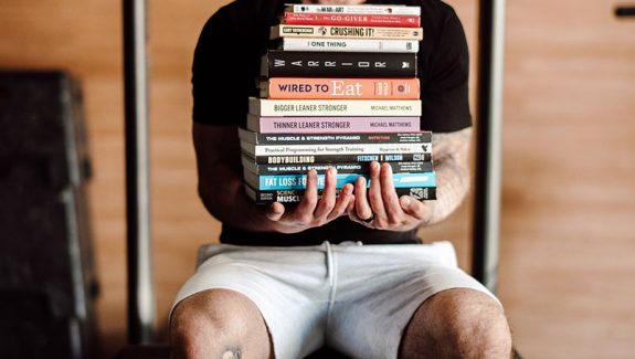 Cody McBroom holding a pile of books