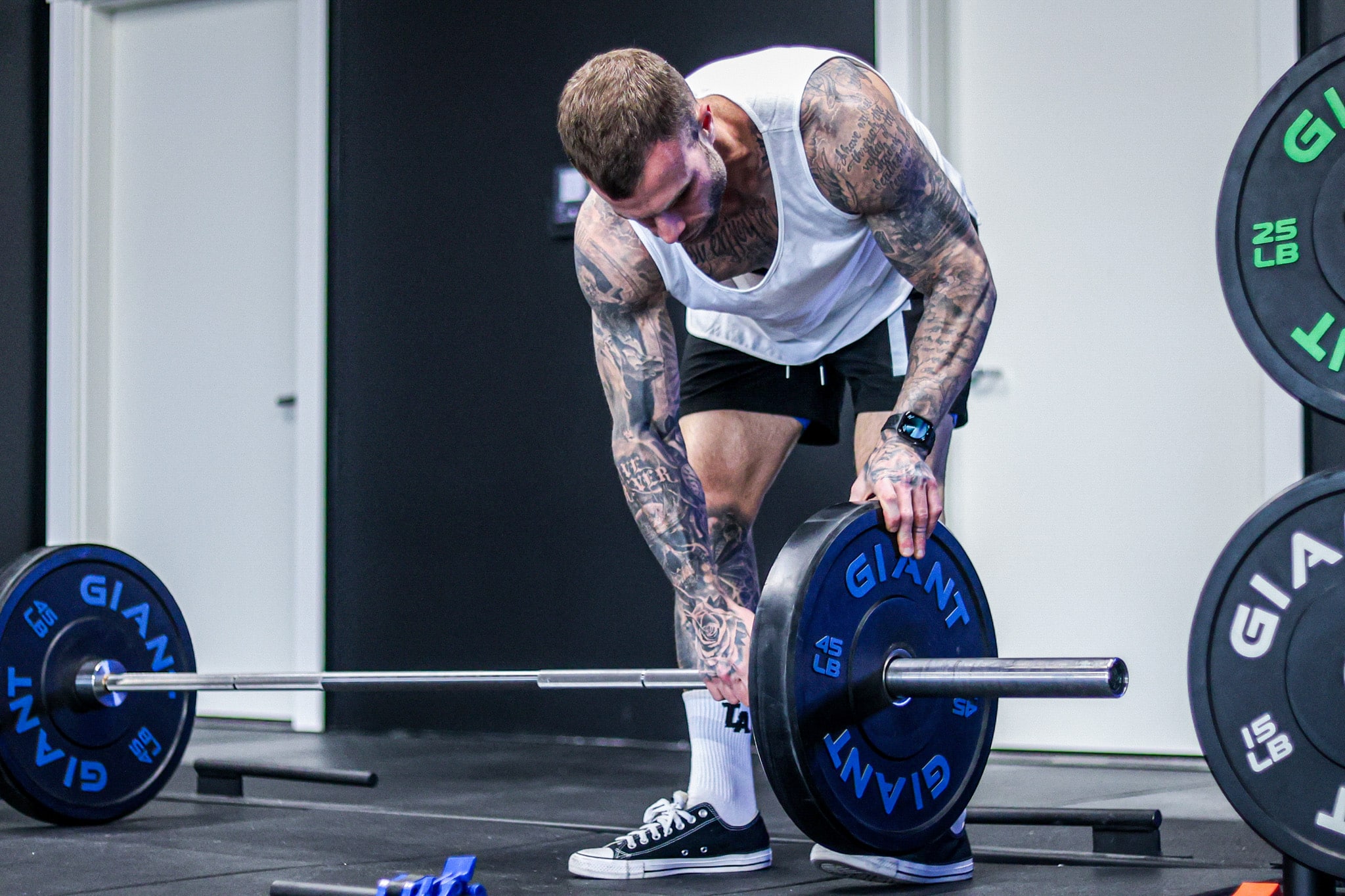 Cody McBroom loading a barbell on a deadlift platform