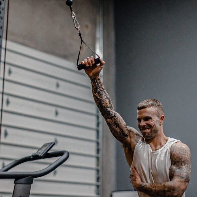 Cody McBroom, owner and founder of Tailored Coaching Method performing single-arm cable lateral raise